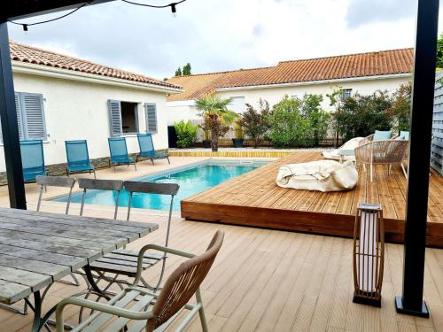 un patio avec une terrasse en bois à côté d'une piscine dans l'établissement Biscarrosse Bourg VILLA AVEC PISCINE, à Biscarrosse