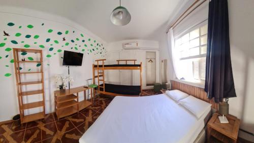 a bedroom with a bed and a large window with green decorations at Pousada - Aqui Hostel in Bragança Paulista