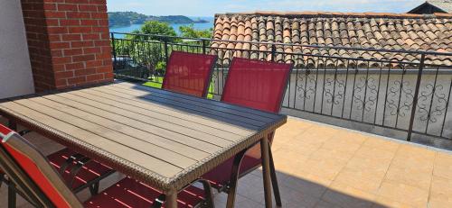 drewniany stół i 2 czerwone krzesła na balkonie w obiekcie Sea view apartment Renzzo w mieście Strunjan