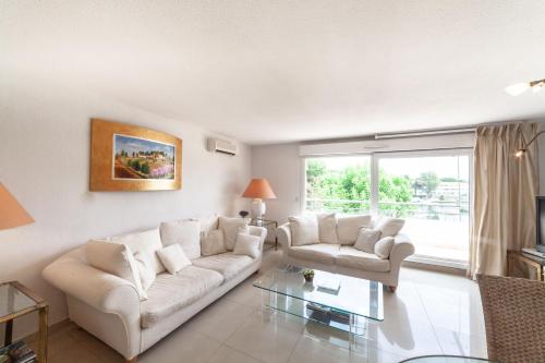 - un salon avec deux canapés blancs et une table en verre dans l'établissement Appartement Mandelieu sur les berges de Siagne, à Mandelieu-la-Napoule