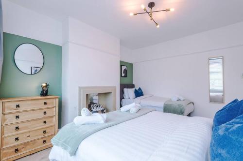 a bedroom with two beds and a dresser and a mirror at Classic 4 Bedroom House in Wirral with WiFi & Parking Sleeps 9 by PureStay in Wirral