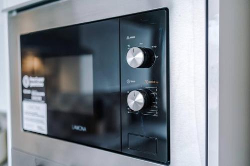 a microwave oven with two knobs on a wall at Classic 4 Bedroom House in Wirral with WiFi & Parking Sleeps 9 by PureStay in Wirral