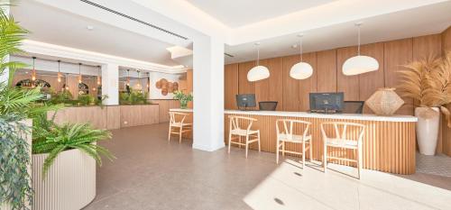 a lobby with a bar with chairs and plants at Flacalco Hotel & Apartments in Cala Ratjada