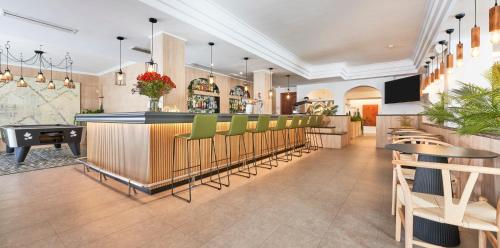 een restaurant met een bar met groene stoelen en tafels bij Flacalco Hotel & Apartments in Cala Ratjada