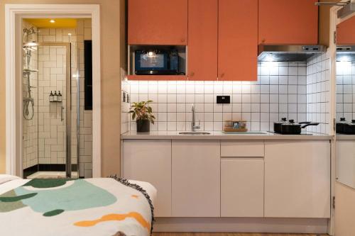 - une cuisine avec des placards orange et blancs et un évier dans l'établissement room2 Hammersmith Townhouse, à Londres