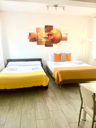 two beds in a hotel room with yellow sheets at 4-Tourist House Bologna-Studio - Self check-in in Bologna