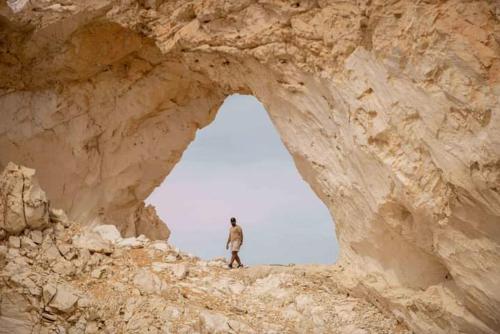 a man standing in a cave in a rocky mountain at الصحراء البيضاء in Bawiti
