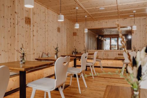 a dining room with wooden tables and white chairs at Ferienalm Panorama Apartments in Schladming