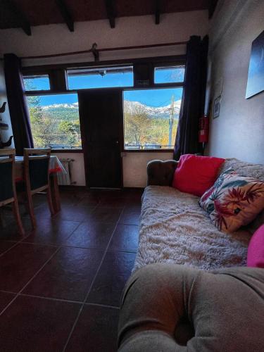 a living room with a couch and a large window at Departamentos Turísticos Saavedra in El Bolsón