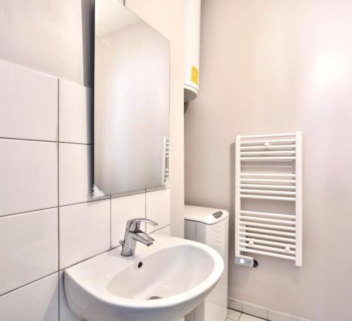 ein weißes Badezimmer mit einem Waschbecken und einem Spiegel in der Unterkunft 833 - Charming studio in Paris Olympic Games 2024 in Paris