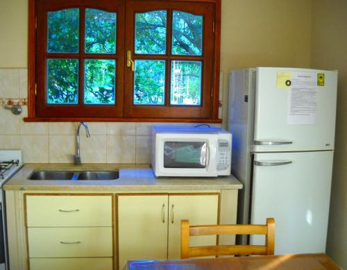 a kitchen with a white refrigerator and a microwave at Cabañas Ronca Hue in Tandil