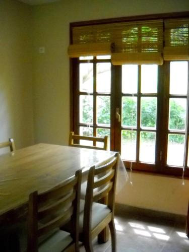 a dining room with a wooden table and two windows at Cabañas Ronca Hue in Tandil