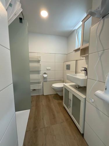 a white bathroom with a toilet and a sink at Ferienwohnung Ella in Marktoberdorf