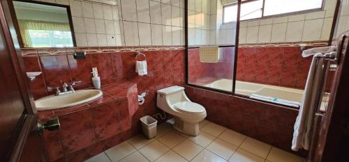 een badkamer met een toilet, een wastafel en een bad bij Apartotel Obelisco San José Aeropuerto in San José