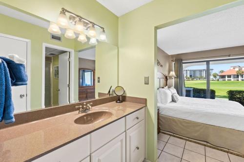 a bathroom with a sink and a bed and a mirror at Edgewater Golf Villa 605 in Panama City Beach