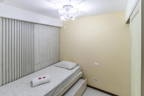 a small bedroom with a bed and a chandelier at Flat Pipa Oceano in Pipa