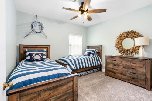 Un dormitorio con dos camas y un ventilador de techo. en Island Time Oasis Pool Walk to Beach and Balcony, en Daytona Beach Shores