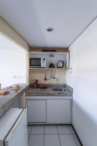 a small kitchen with a sink and a microwave at Flat Pipa Oceano in Pipa
