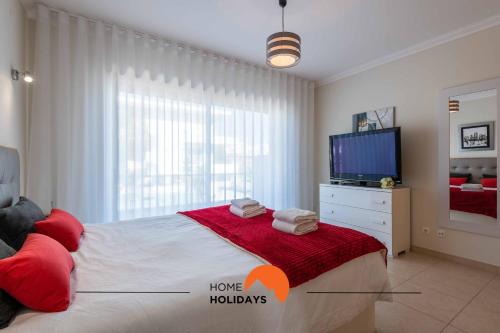 a bedroom with a large bed and a tv at #226 Vila LII by Home Holidays in Albufeira
