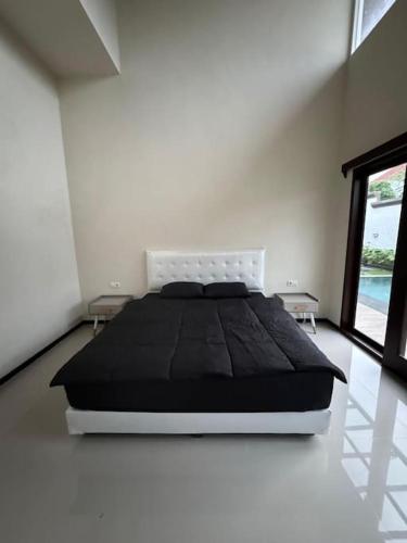 a bedroom with a black bed in a white room at Villa Medea Banyuwangi in Banyuwangi