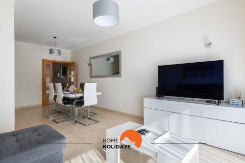 a living room with a television and a table with chairs at #226 Vila LII by Home Holidays in Albufeira