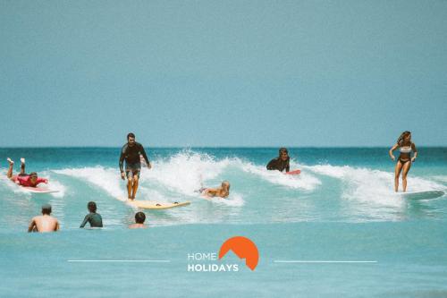 a group of people riding a wave on surfboards in the ocean at #226 Vila LII by Home Holidays in Albufeira