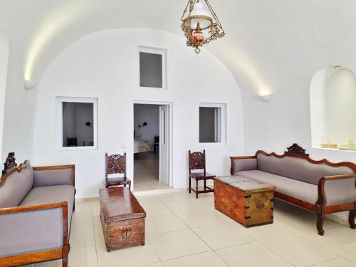 a living room with couches and chairs and a chandelier at Karpimo Horizon - Caldera View with private hot tub in Firostefani