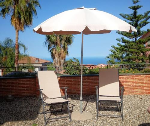 two chairs and an umbrella on a patio at Villa Hirschen in Zafferana Etnea