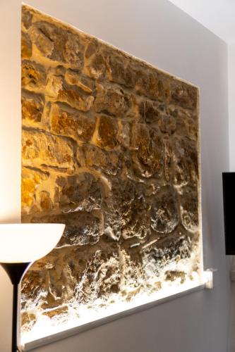 a stone wall in a room with a lamp at L'ombelico del Monte - appartamenti in centro storico in Piazza Armerina
