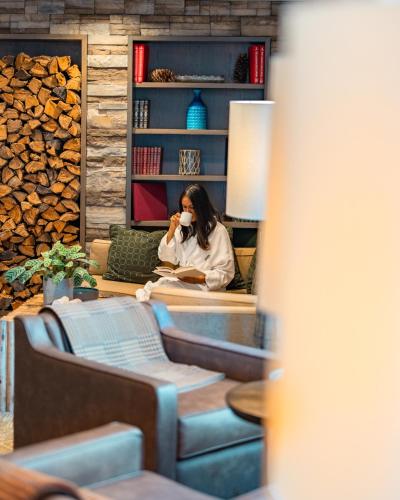 a woman drinking a cup of coffee in a living room at Fairmont Jasper Park Lodge in Jasper
