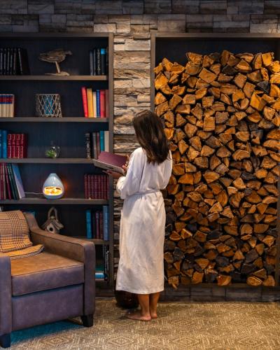a woman reading a book in front of a pile of fire wood at Fairmont Jasper Park Lodge in Jasper