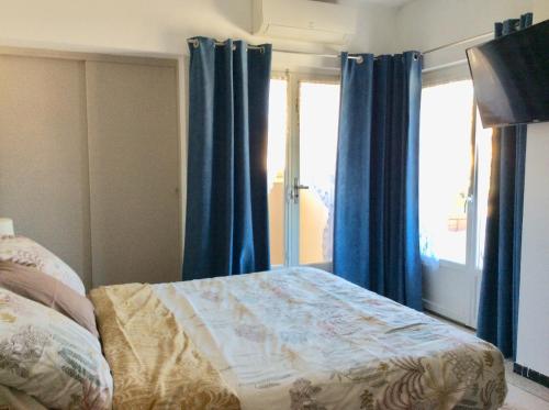 - une chambre avec des rideaux bleus, un lit et une fenêtre dans l'établissement Spacieux 2 pièces, au Cannet