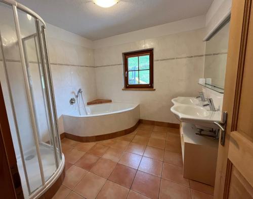 uma casa de banho com uma banheira, 2 lavatórios e um chuveiro em Rasterhof em Sillian