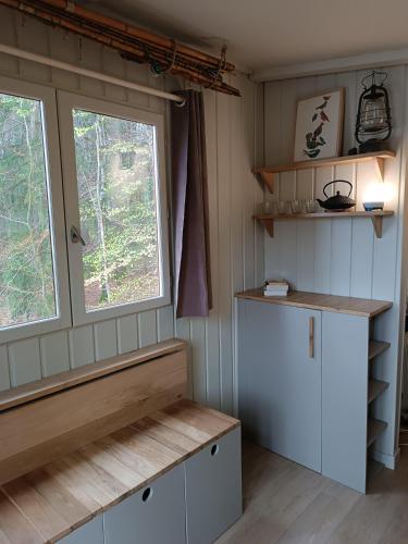 une petite cuisine avec une fenêtre et un banc dans l'établissement Les cabanes au bord du lac, à Saint-Gérons