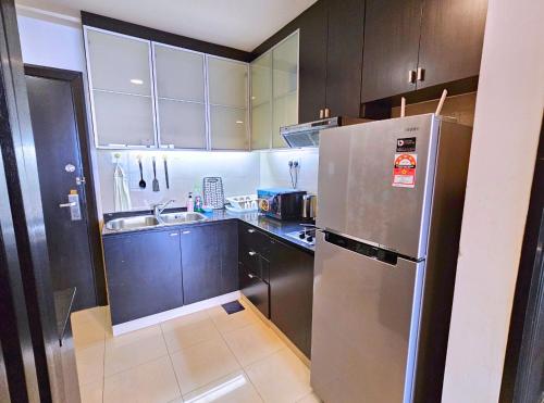 a kitchen with brown cabinets and a stainless steel refrigerator at Sunway Studio HomeStay Access Mall & next to Lagoon by Cloud Host in Petaling Jaya