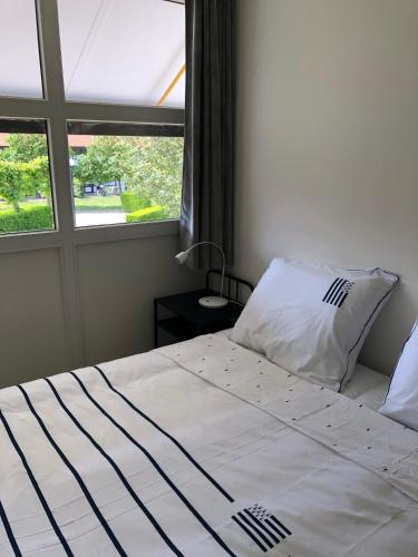 a bedroom with a white bed with a window at Crevette, vakantiehuis voor 6 personen in Middelkerke