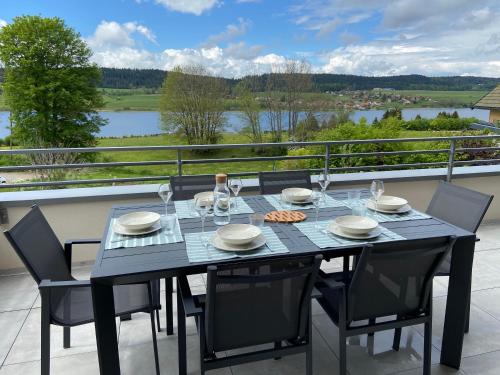 a dining table with chairs and a view of a river at Duplex 6 personnes, vue panoramique sur lac in Malbuisson