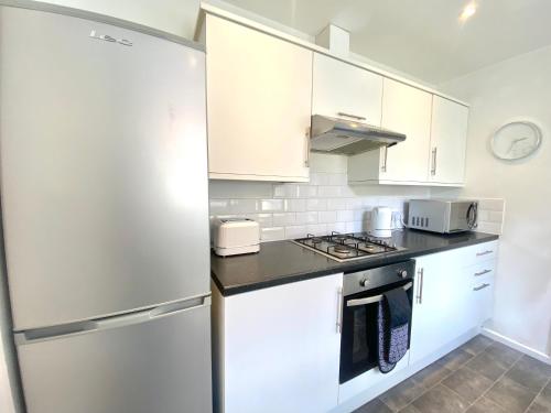 a kitchen with white cabinets and a refrigerator at Rushden - Spacious House and Garden, Free Parking, TV, Sleeps 8 Guests in Rushden