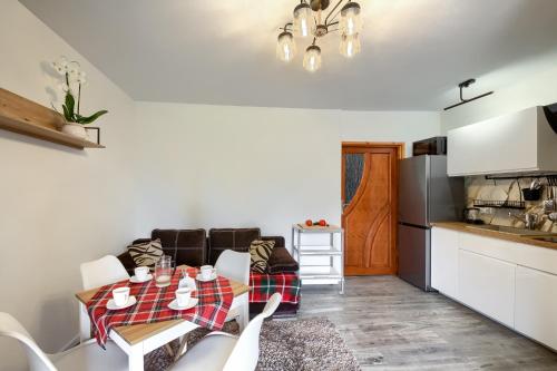 a living room with a table and a kitchen at Apartamenty Szwarcowa in Tylicz