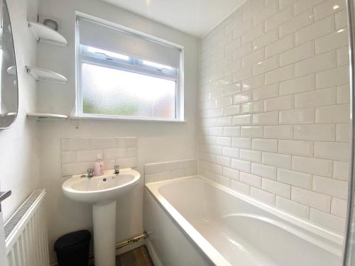 a white bathroom with a sink and a bath tub at Stylish 5 Beds House, TV, Garden in Rushden
