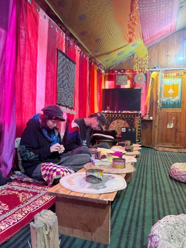 two people sitting at tables in a room with colorful walls at Old Brahma Homestay in Kalgha
