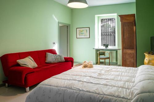 a red couch and a red bed in a room at Cascina Ambrosia Residenza d'Epoca in Asti