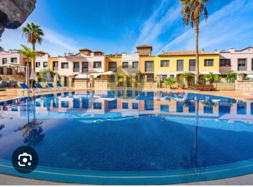 Una gran piscina con palmeras y edificios. en Luxury Beach Villa, en Adeje