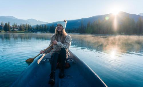 a woman paddling a canoe on a lake at Fairmont Jasper Park Lodge in Jasper