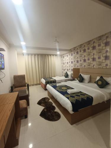 a hotel room with two beds and a chair at Hotel Grand Suites By D'Capitol Near IGI Airport in New Delhi
