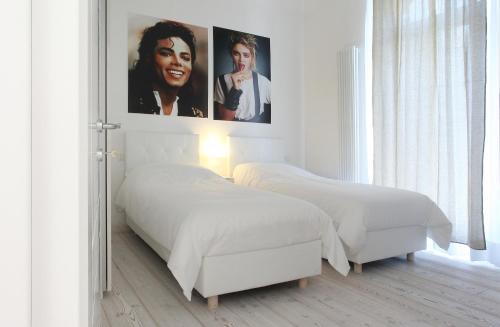 two beds in a white bedroom with posters on the wall at Big Johnny B in Rome