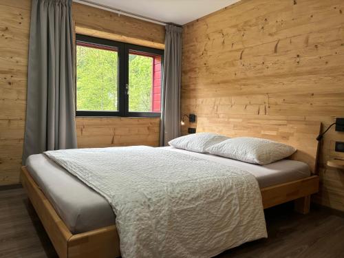 a bedroom with a bed and a wooden wall at La Ferme de Rochesson, Jacuzzis privatif & Piscine commune in Rochesson