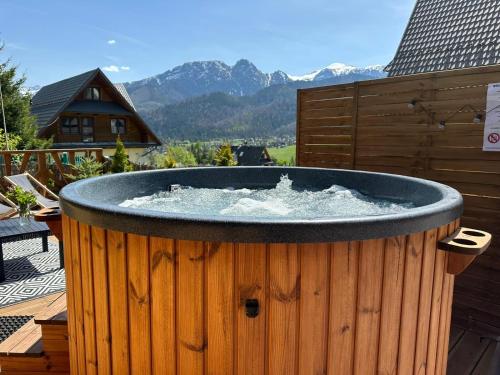 a hot tub on a deck with mountains in the background at Wierchowe Domki z jacuzzi in Kościelisko