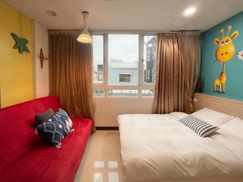 a bedroom with a red couch and a giraffe mural at 斑比Bambi in Tainan
