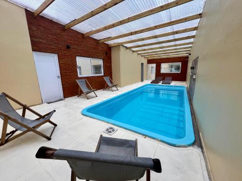 a swimming pool in a room with chairs and a table at Hotel Los Angeles in Santa Teresita
